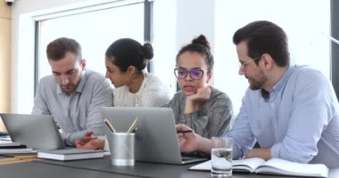 Çok kültürlü iş adamları dizüstü bilgisayarlar kullanarak dijital pazarlama araştırması yapıyorlar.