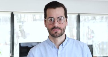 İş yerinde poz veren erkek patron kameraya bakıyor.