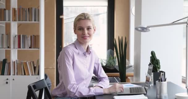 Hermosa mujer de negocios sentarse en el escritorio del lugar de trabajo sonriendo mirando a la cámara — Vídeos de Stock