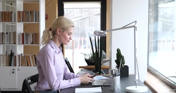 Женщина, сидящая за столом чата использовать мобильный телефон — стоковое видео