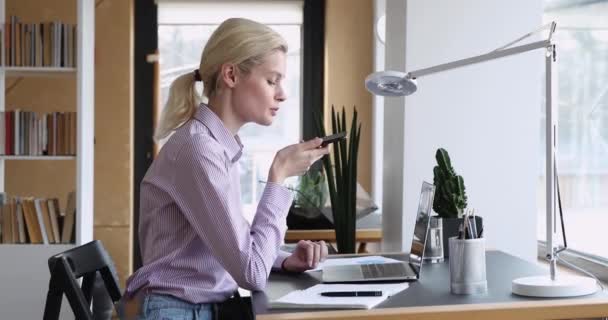 Affärskvinna sitter vid skrivbordet lösa problem med kunden genom högtalartelefon — Stockvideo