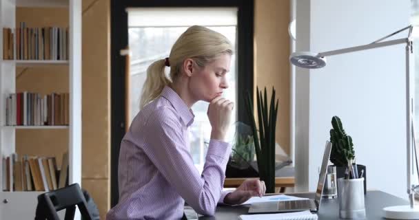 Vrouwelijke werknemer zit aan de werkplek bureau werken op laptop — Stockvideo