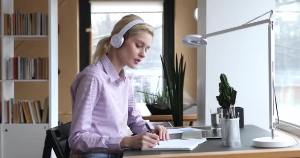 Mulher usa fones de ouvido conversar com tutor por notebook e videoconferência — Vídeo de Stock