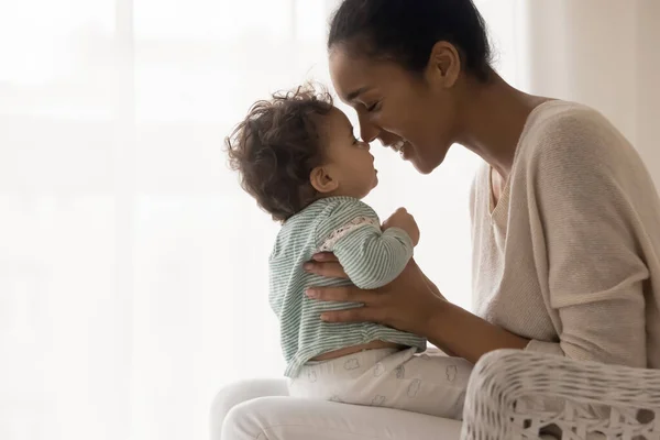 Usmívající se mladá africká americká maminka dotýkající se nosy s roztomilé dítě. — Stock fotografie