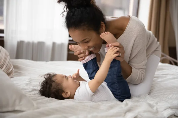Sonriendo cariñosa madre birracial divertirse con el niño en el dormitorio. — Foto de Stock