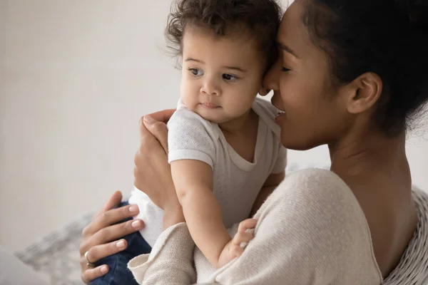Zorgen voor jong gemengd ras moeder knuffelen weinig biracial baby. — Stockfoto