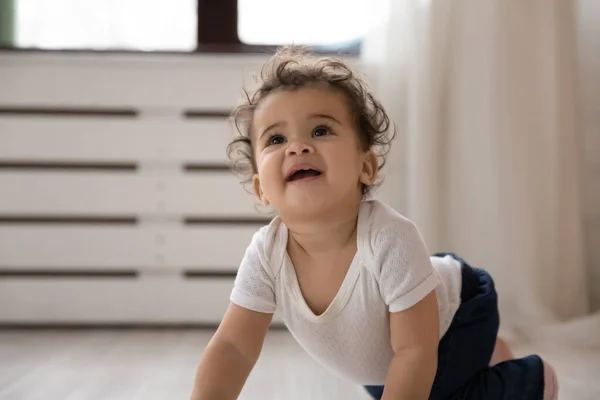 Grappig klein Afrikaans Amerikaans baby kruipen op houten warme vloer. — Stockfoto