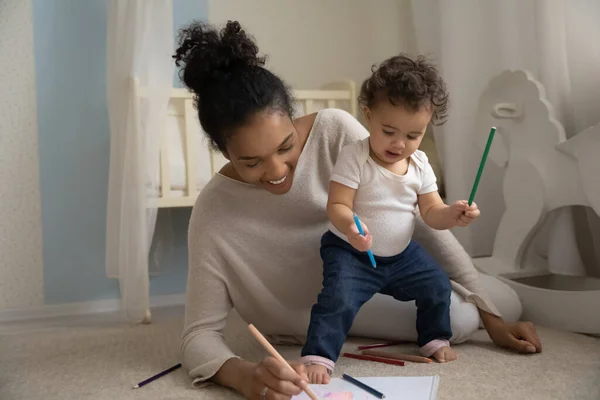 Sorrindo carinhoso jovem afro-americano mamãe ensinando pequeno bebê desenho. — Fotografia de Stock