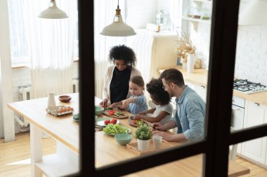 İçerde yemek pişiren mutlu uluslararası aile..