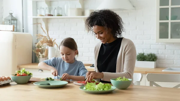 Afrikanische amerikanische Mutter kocht Essen mit europäischer Tochter. — Stockfoto