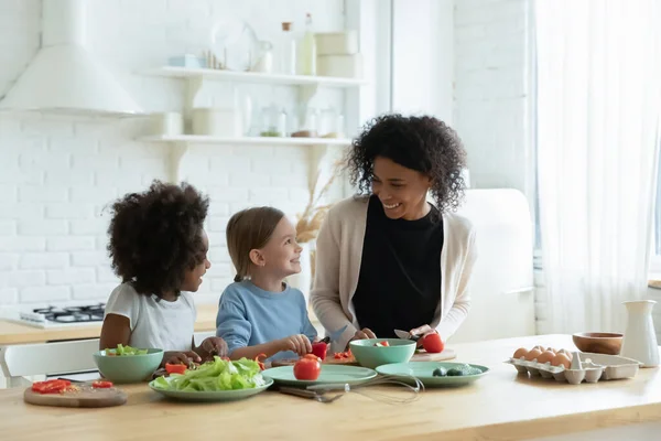 Fröhliche gemischte Rassenfamilie bereitet in Küche gemeinsam Essen zu. — Stockfoto