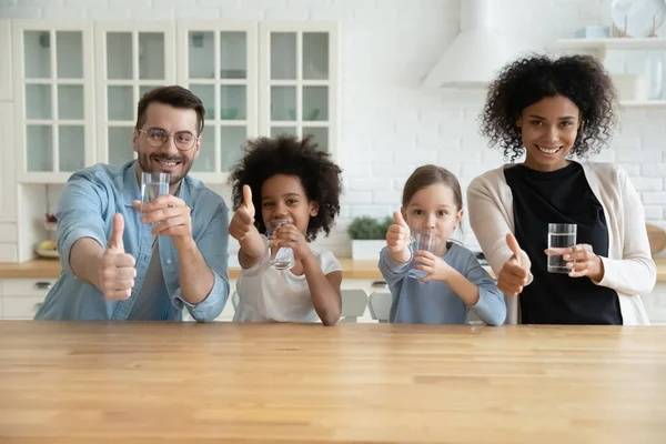 Glückliche gesunde Mischlingsfamilie empfiehlt Trinkwasser. — Stockfoto