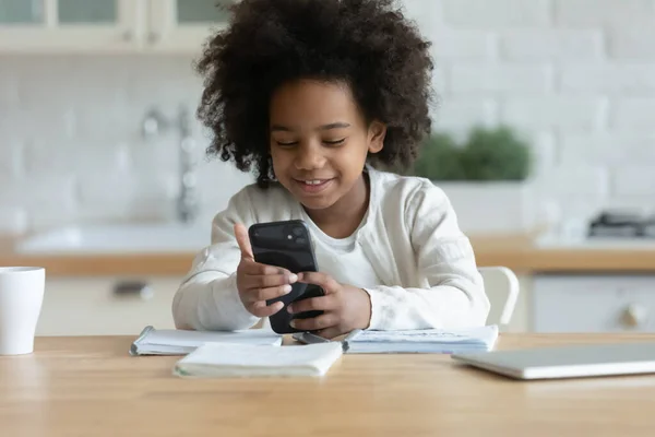 Szczęśliwy mały afrykański pochodzenie etniczne dwurasowe dziecko zaangażowane w gry mobilne. — Zdjęcie stockowe