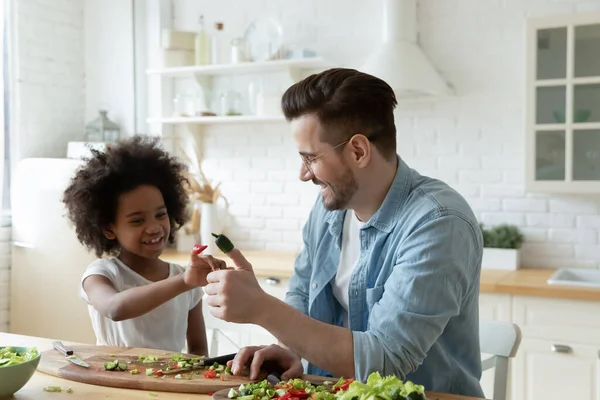 Lächelnder junger hübscher Vater scherzt mit birassischer Adoptivtochter. — Stockfoto