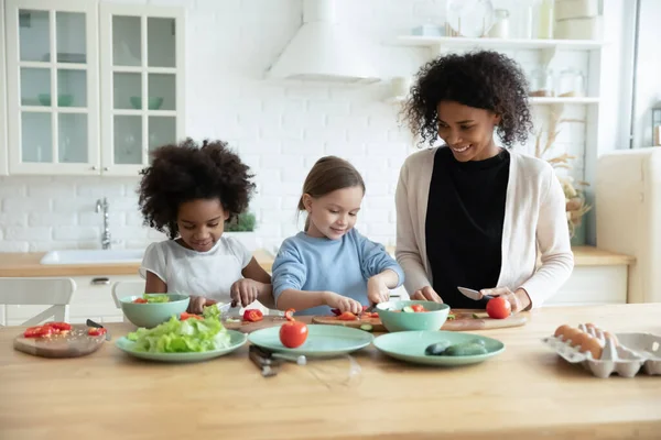 Cuidar a la mamá afroamericana enseñando a cocinar a las niñas. —  Fotos de Stock