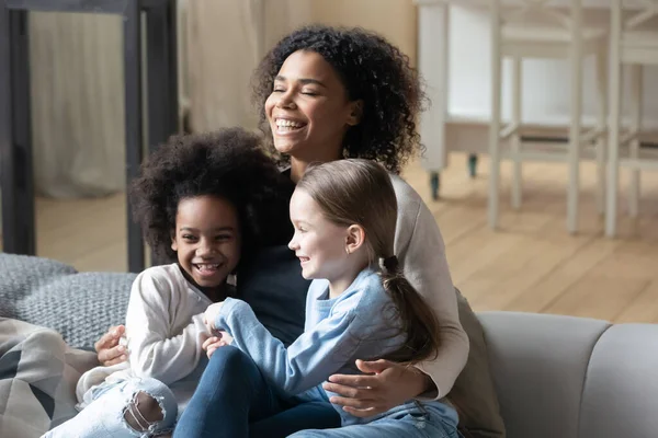 Happy young african american woman cuddling playful diverse daughters. — Stock Photo, Image