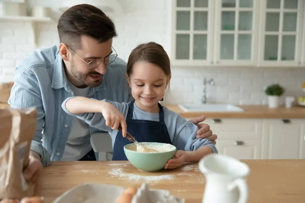 幼い娘が料理を作るのを手伝ってくれる父親を介護する. — ストック写真