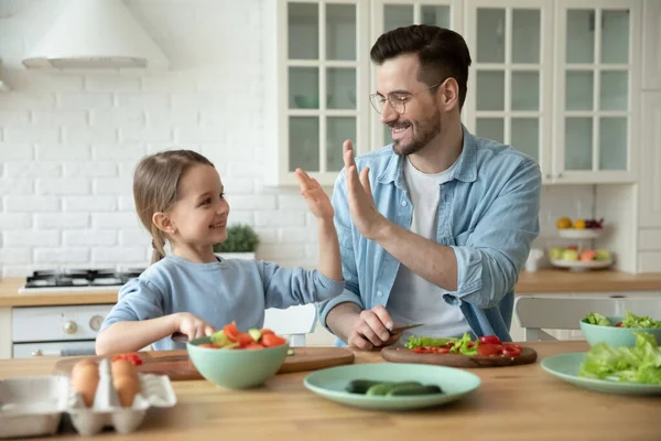 Petite fille donnant haute cinq à père aimant dans la cuisine. — Photo