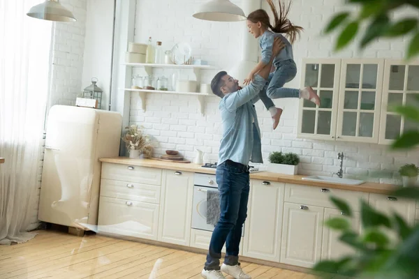 Havada küçük bir anaokulu kızını kaldıran mutlu genç adam..