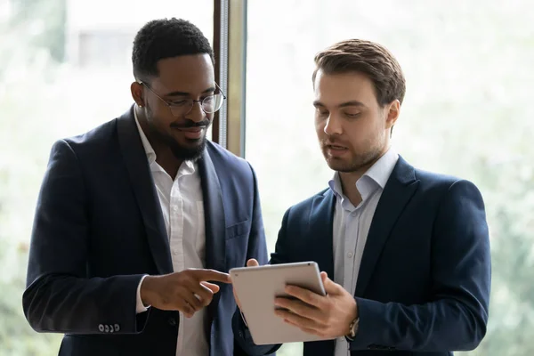 Glimlachende multi-etnische collega 's werken samen aan tablet — Stockfoto