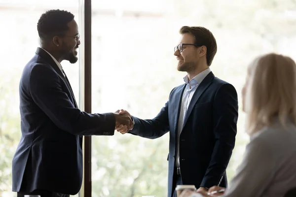 Happy male colleagues shake hands in office — Stock Photo, Image