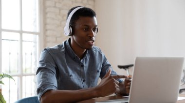 Amerikalı kulaklıklı erkek bir Afrikalı çalışanın video çağrısı var.