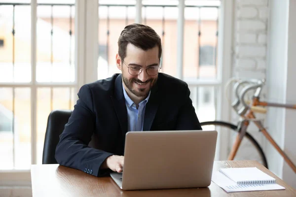 Sorrindo homem de negócios caucasiano ocupado usando laptop moderno — Fotografia de Stock