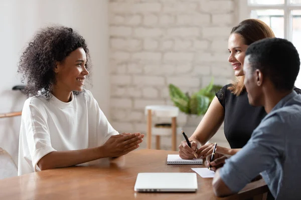 Smiling biracial woman talk with employers at job interview
