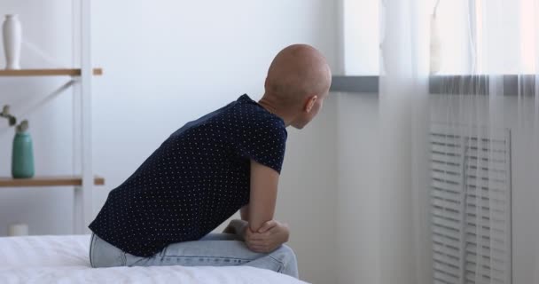 Mujer calva paciente de cáncer sentado en la cama mirando por la ventana — Vídeo de stock