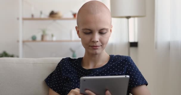 Mulher jovem sem pêlos usar mensagem de texto tablet sentado no sofá — Vídeo de Stock