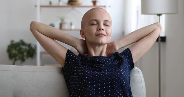 Bald calm girl put hands behind head relaxing on sofa — Stock Video