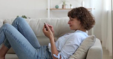 Orta yaşlı kadın kanepede dinleniyor. Akıllı telefon kullan.