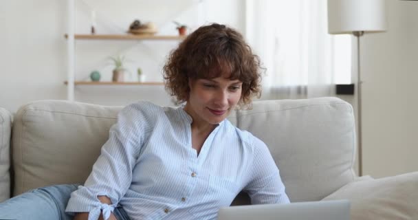 Mujer acostada en el sofá uso portátil leer noticias se siente feliz — Vídeos de Stock