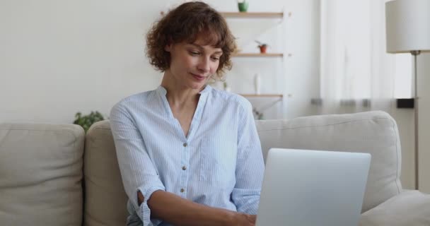 Mujer de mediana edad sentarse en el sofá con el ordenador portátil leer noticias risas — Vídeos de Stock