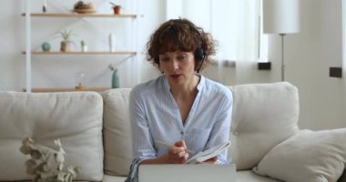 İnternetteki öğretmenle video görüşmesi sırasında kulaklık takan bir kadın.