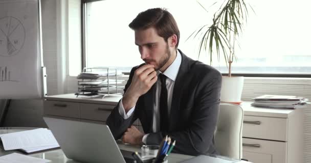 Сосредоточенный молодой бизнесмен думает о решении проблем в офисе. — стоковое видео