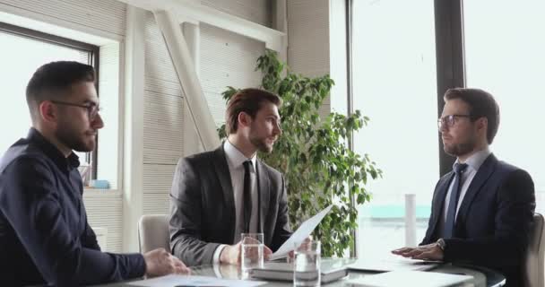 Multiraciala affärsmän i kostym diskuterar avtal partnerskap detaljer vid mötet. — Stockvideo