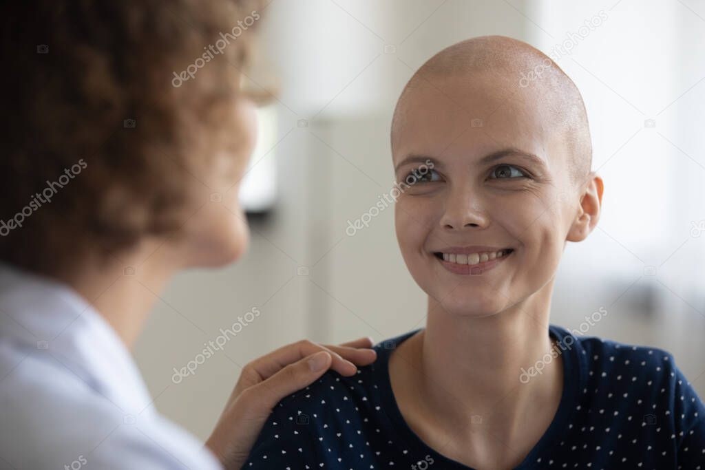 Smiling sick young female cancer patient talk with doctor