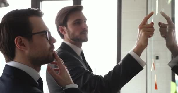 Geconcentreerde mannelijke werknemers die projectworkflow beheren met plakkerige notities. — Stockvideo
