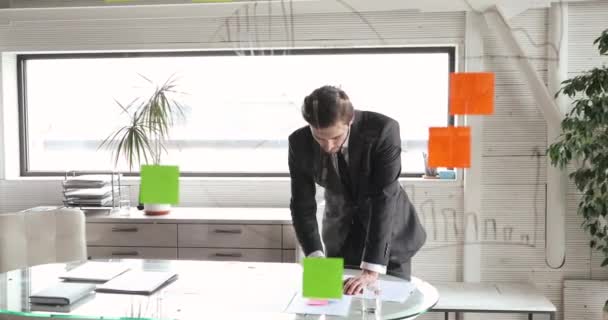 Konzentrierte Führungspersönlichkeit, die Arbeitsabläufe mit papiernen Erinnerungen steuert. — Stockvideo