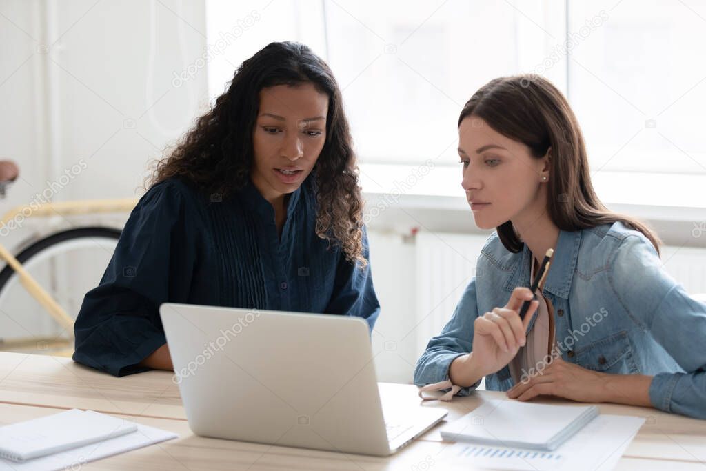 African American businesswoman mentor training intern, using laptop