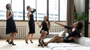 Mutlu siyah elbiseli dört zarif kadın parti zamanı.