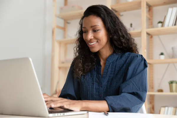 Leende afroamerikansk affärskvinna med bärbar dator, tittar på skärmen — Stockfoto