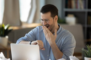 Yorgun genç erkek işçi iç geçiriyor. İşi bitirene kadar bekle.