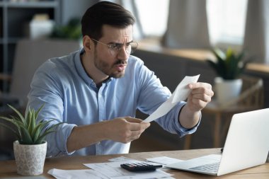 Faturaları internet üzerinden ödemekten sıkılmış mutsuz genç bir adam.