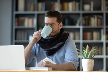 Sağlıksız genç adam gripten muzdarip çay içiyor.