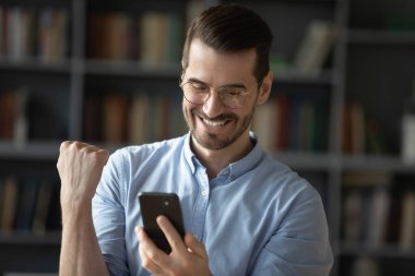 Heyecanlı bir adam cep telefonunda mutluluk dolu bir mesaj okuyor.