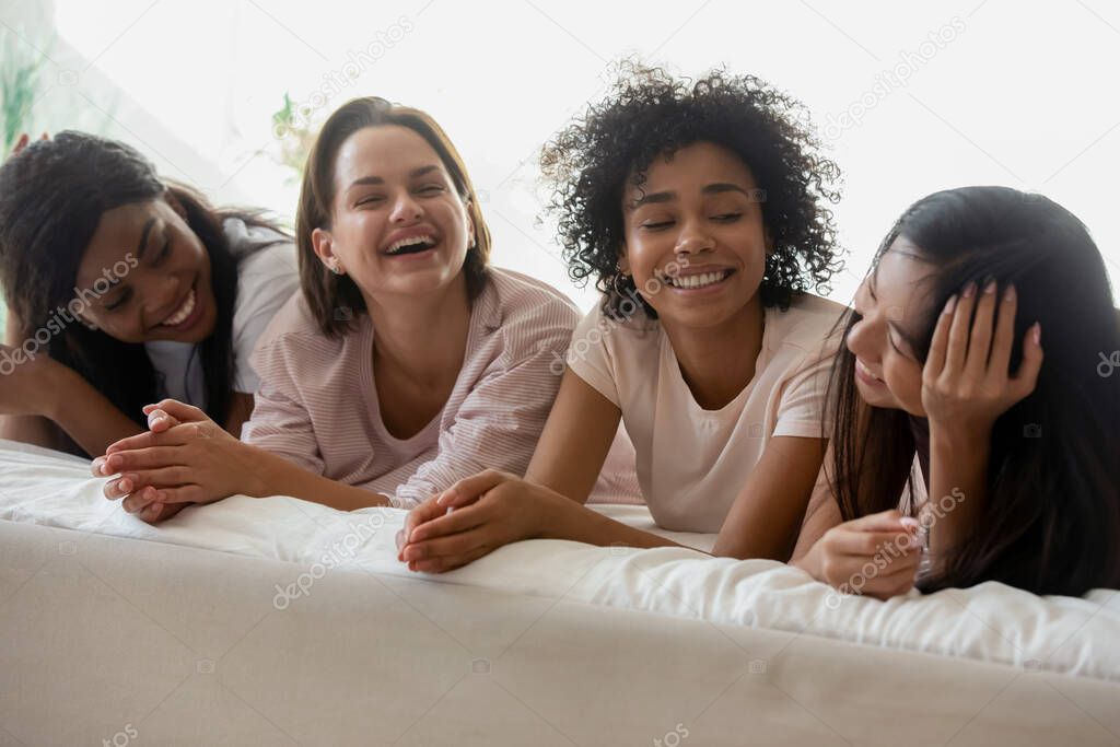 Overjoyed happy sincere young multiracial friends enjoying sleepover party.