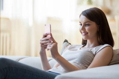 Evde cep telefonu kullanan genç bayan.