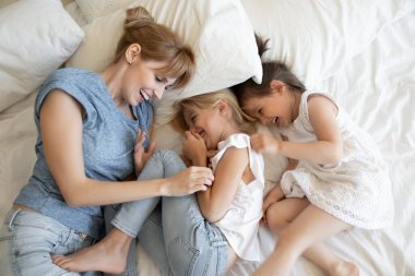 Neşeli anne ve kızları yatakta dinleniyor.